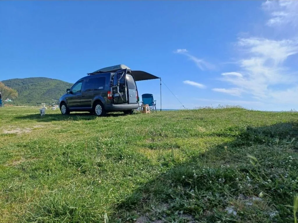VW Caddy Life camper on a grassy coastal field